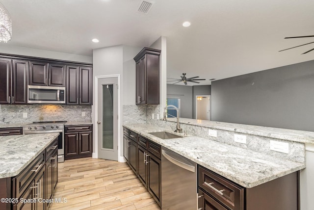 3735 Crista Jean Ave, Grant-Valkaria, FL 32909 - kitchen with stainless steel appliances, a ceiling fan, light wood finished floors, a peninsula, and backsplash