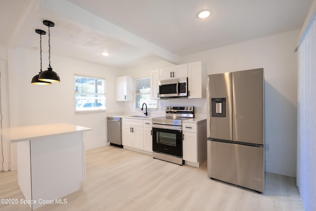 1810 Dixon Blvd, Cocoa, FL 32922 - kitchen featuring stainless steel appliances, light countertops, light wood-style flooring, white cabinetry, and hanging light fixtures