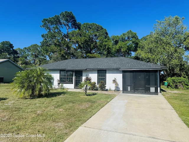 5685 Jamaica Rd, Cocoa, FL 32927 - view of front of house with driveway, a front lawn, a shingled roof, and a sunroom