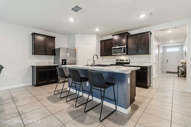 1809 Morely Dr, Cocoa, FL 32926 - kitchen with stainless steel appliances, light countertops, a breakfast bar area, light tile patterned floors, and dark brown cabinets