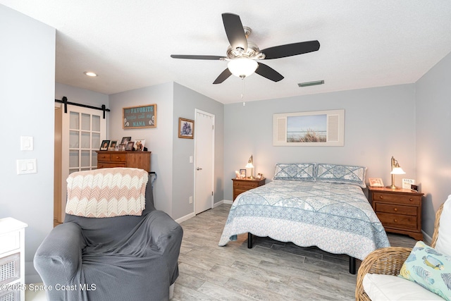 1100 SE Mitchell Ave Unit 204, Port St Lucie, FL 34952 - bedroom with light wood finished floors, a barn door, ceiling fan, and recessed lighting