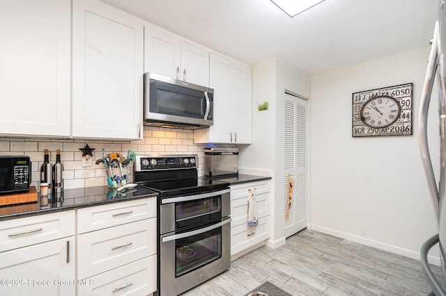 1100 SE Mitchell Ave Unit 204, Port St Lucie, FL 34952 - kitchen with stainless steel appliances, tasteful backsplash, white cabinetry, light wood-style flooring, and dark stone countertops