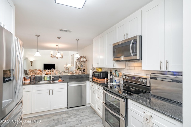 1100 SE Mitchell Ave Unit 204, Port St Lucie, FL 34952 - kitchen featuring appliances with stainless steel finishes, white cabinets, tasteful backsplash, a chandelier, and hanging light fixtures