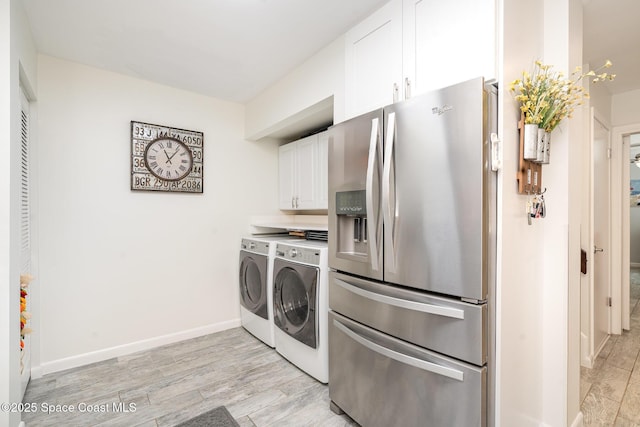 1100 SE Mitchell Ave Unit 204, Port St Lucie, FL 34952 - kitchen with stainless steel fridge, separate washer and dryer, white cabinets, and light wood-type flooring