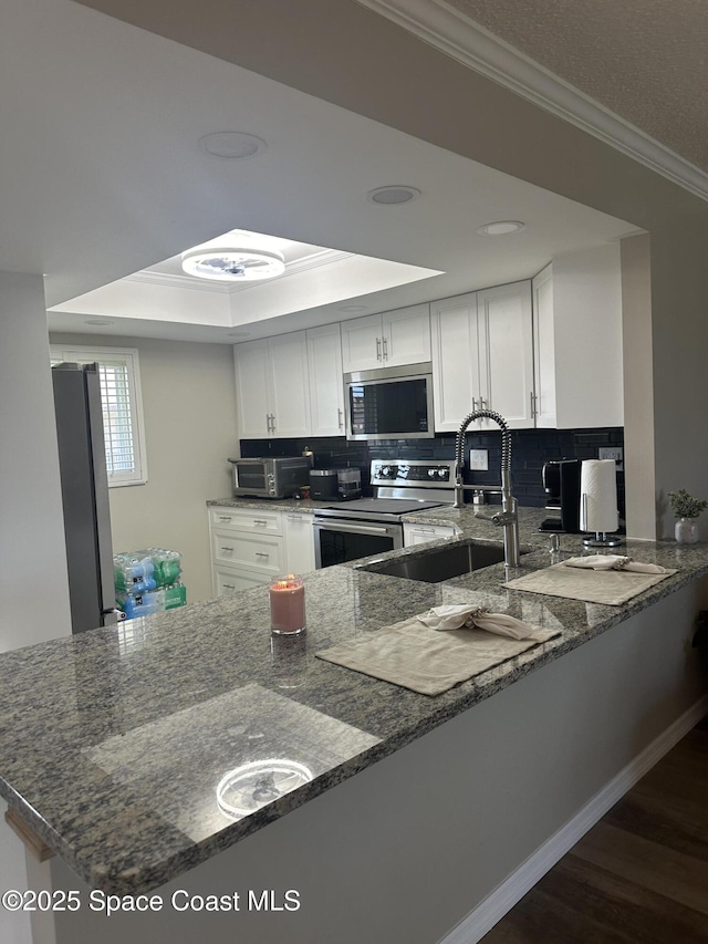 3210 N Harbor City Blvd Unit 316, Melbourne, FL 32935 - kitchen featuring stainless steel appliances, ornamental molding, white cabinetry, backsplash, and a peninsula