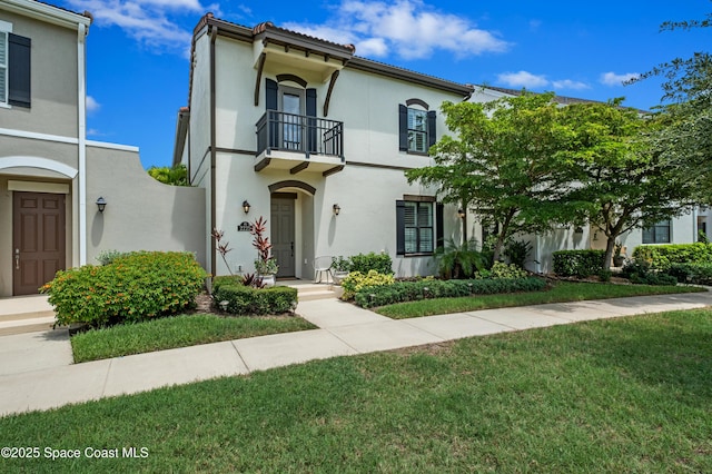 2225 Framura Ln, Melbourne, FL 32940 - mediterranean / spanish home featuring a balcony, stucco siding, and a front lawn