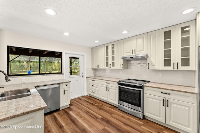 2150 Winston Dr, Cocoa, FL 32926 - kitchen featuring appliances with stainless steel finishes, under cabinet range hood, a textured ceiling, backsplash, and light stone countertops