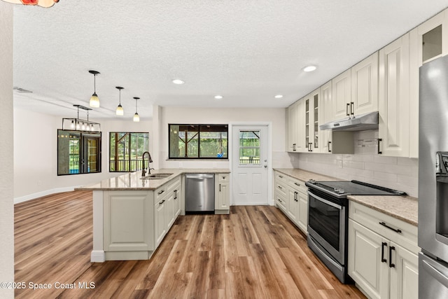 2150 Winston Dr, Cocoa, FL 32926 - kitchen with stainless steel appliances, under cabinet range hood, a peninsula, light wood finished floors, and recessed lighting