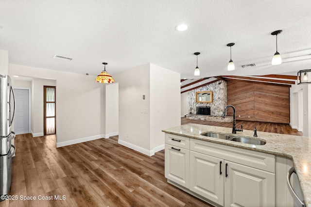 2150 Winston Dr, Cocoa, FL 32926 - kitchen with freestanding refrigerator, white cabinetry, a textured ceiling, light stone counters, and decorative light fixtures