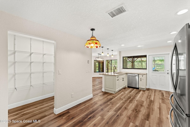 2150 Winston Dr, Cocoa, FL 32926 - kitchen with appliances with stainless steel finishes, wood finished floors, light countertops, healthy amount of natural light, and a textured ceiling