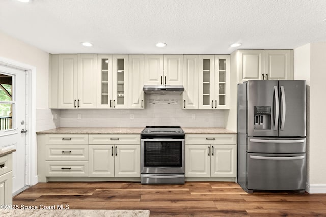 2150 Winston Dr, Cocoa, FL 32926 - kitchen with appliances with stainless steel finishes, under cabinet range hood, backsplash, glass insert cabinets, and a textured ceiling