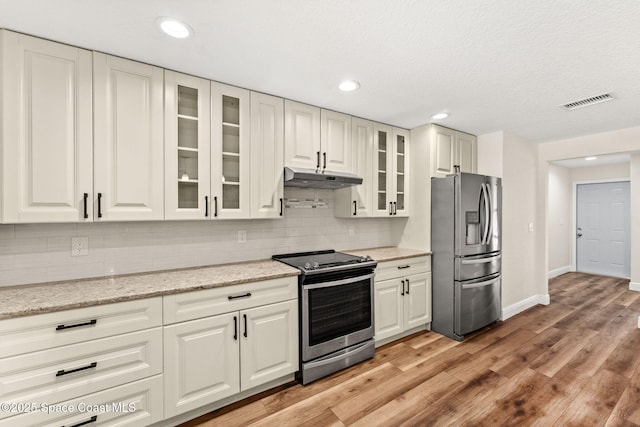 2150 Winston Dr, Cocoa, FL 32926 - kitchen with appliances with stainless steel finishes, under cabinet range hood, backsplash, light wood-type flooring, and glass insert cabinets