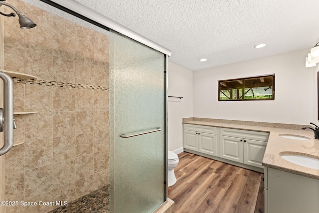 2150 Winston Dr, Cocoa, FL 32926 - bathroom featuring a stall shower, a textured ceiling, double vanity, wood finished floors, and recessed lighting