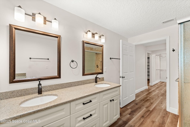 2150 Winston Dr, Cocoa, FL 32926 - bathroom featuring wood finished floors, double vanity, and a textured ceiling