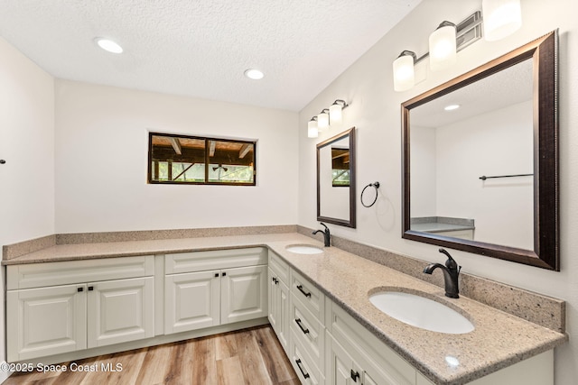 2150 Winston Dr, Cocoa, FL 32926 - full bathroom featuring double vanity, a textured ceiling, wood finished floors, and recessed lighting