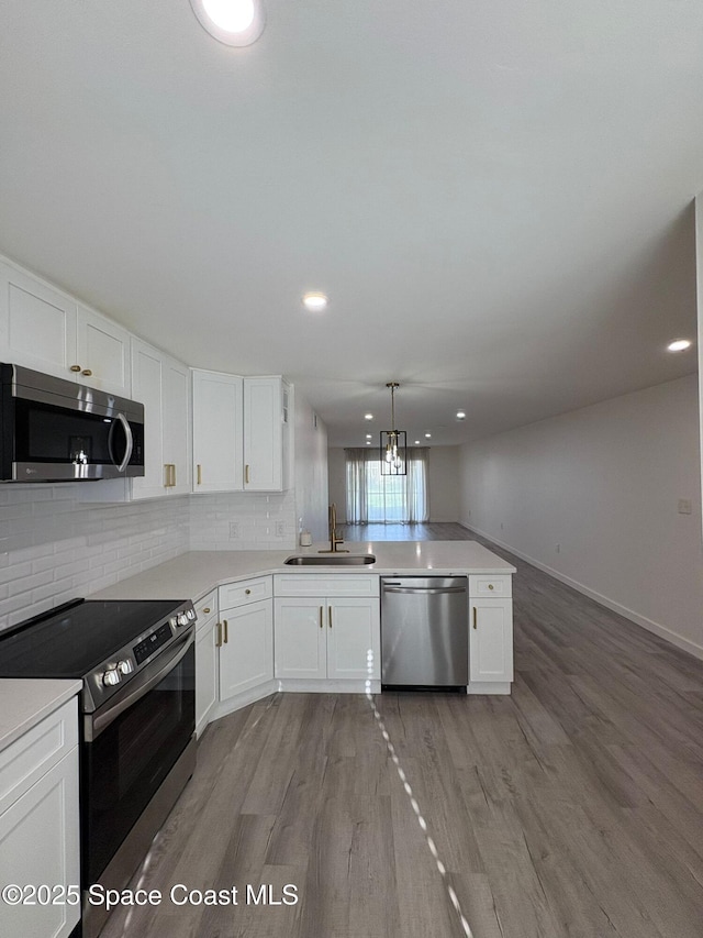 1515 Huntington Ln Unit 915, Rockledge, FL 32955 - kitchen featuring appliances with stainless steel finishes, a peninsula, white cabinets, backsplash, and recessed lighting