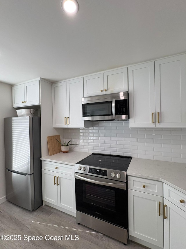 1515 Huntington Ln Unit 915, Rockledge, FL 32955 - kitchen with appliances with stainless steel finishes, white cabinets, light wood finished floors, and decorative backsplash