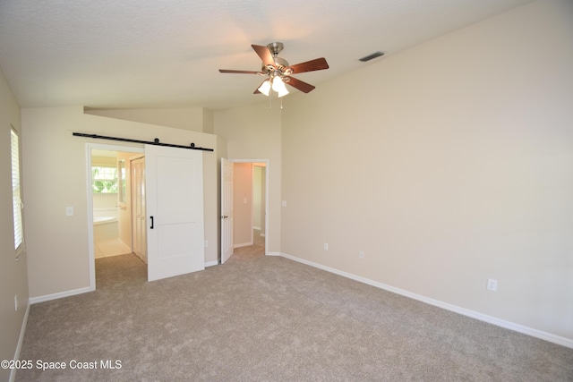 741 Pebble Ave NE, Palm Bay, FL 32907 - unfurnished bedroom with vaulted ceiling, carpet, a barn door, and ceiling fan
