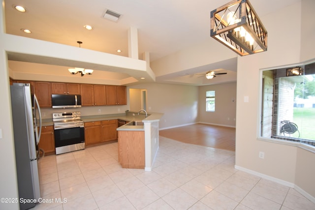 741 Pebble Ave NE, Palm Bay, FL 32907 - kitchen with appliances with stainless steel finishes, a peninsula, brown cabinetry, open floor plan, and recessed lighting