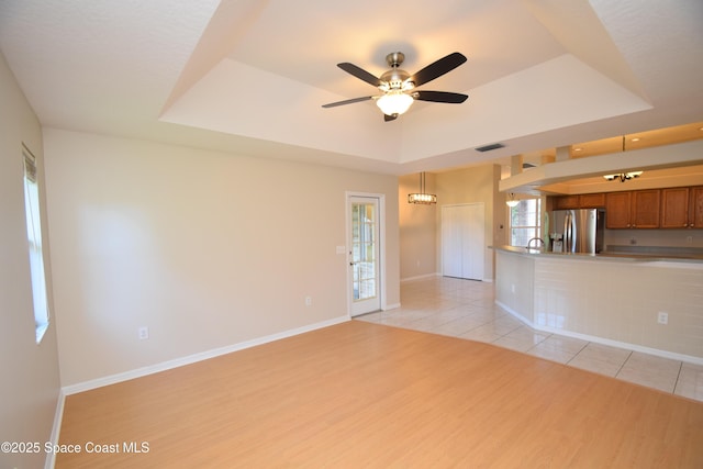 741 Pebble Ave NE, Palm Bay, FL 32907 - unfurnished living room with a tray ceiling, light wood-style floors, and a ceiling fan