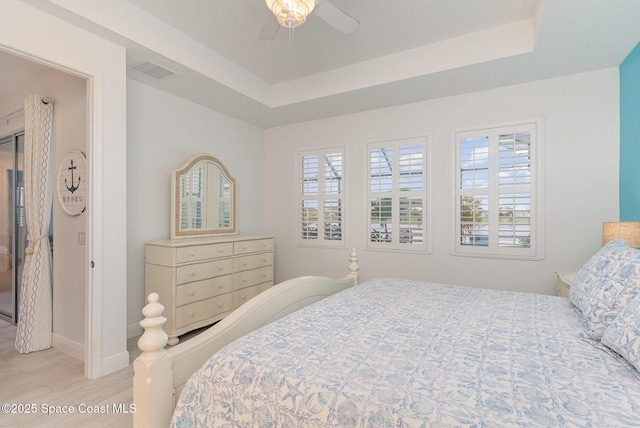 9124 Corvo Ct, Melbourne, FL 32940 - bedroom with multiple windows, light wood finished floors, a tray ceiling, and a ceiling fan