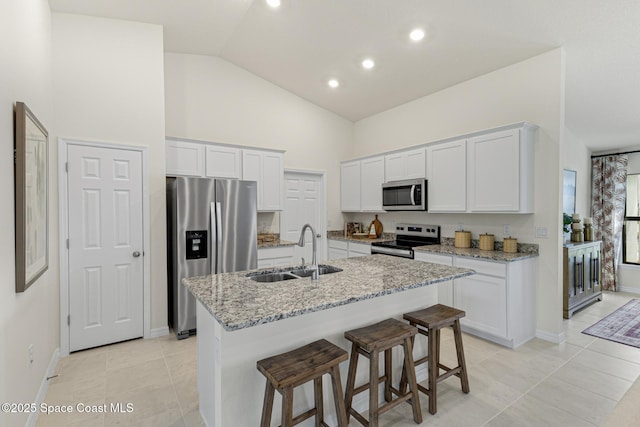 1011 Eldron Blvd SE, Palm Bay, FL 32909 - kitchen featuring stainless steel appliances, white cabinetry, light stone counters, a kitchen island with sink, and a kitchen bar