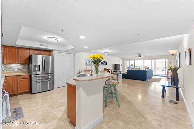 121 Lancha Cir Unit 203, Indian Harbour Beach, FL 32937 - kitchen featuring stainless steel refrigerator with ice dispenser, brown cabinetry, a raised ceiling, light countertops, and recessed lighting