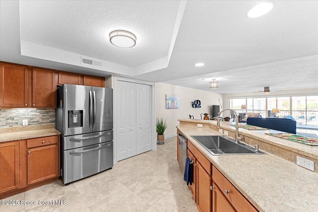 121 Lancha Cir Unit 203, Indian Harbour Beach, FL 32937 - kitchen featuring appliances with stainless steel finishes, brown cabinets, a tray ceiling, a textured ceiling, and light countertops