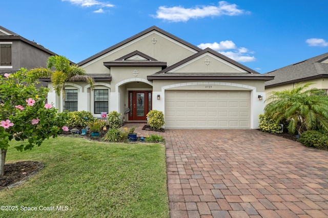 4729 Alligator Flag Cir, West Melbourne, FL 32904 - view of front of home featuring decorative driveway, a front yard, stucco siding, and a garage