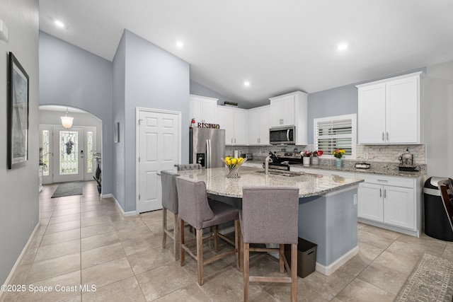 4729 Alligator Flag Cir, West Melbourne, FL 32904 - kitchen featuring appliances with stainless steel finishes, tasteful backsplash, vaulted ceiling, a center island with sink, and white cabinets