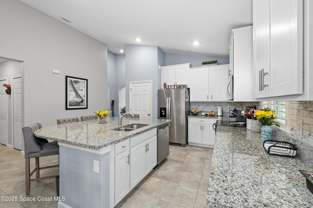 4729 Alligator Flag Cir, West Melbourne, FL 32904 - kitchen featuring appliances with stainless steel finishes, backsplash, light stone countertops, a kitchen bar, and white cabinets