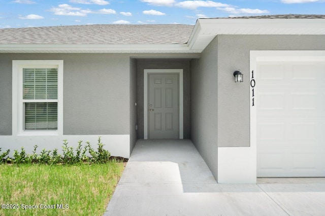 1011 Webster Rd SE, Palm Bay, FL 32909 - view of exterior entry featuring stucco siding, an attached garage, and roof with shingles