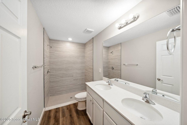 1011 Webster Rd SE, Palm Bay, FL 32909 - full bathroom with a tile shower, double vanity, wood finished floors, and a textured ceiling