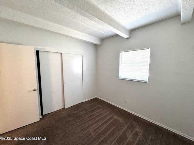 1715 Dixon Blvd Unit 102, Cocoa, FL 32922 - unfurnished bedroom featuring a closet, dark colored carpet, a textured ceiling, and beam ceiling