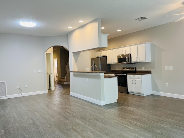 117 Anchorage Ave Unit 6, Cape Canaveral, FL 32920 - kitchen with appliances with stainless steel finishes, arched walkways, wood finished floors, white cabinetry, and recessed lighting