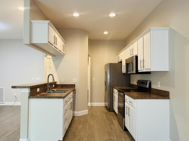 117 Anchorage Ave Unit 6, Cape Canaveral, FL 32920 - kitchen with stainless steel appliances, dark countertops, wood finished floors, white cabinets, and recessed lighting
