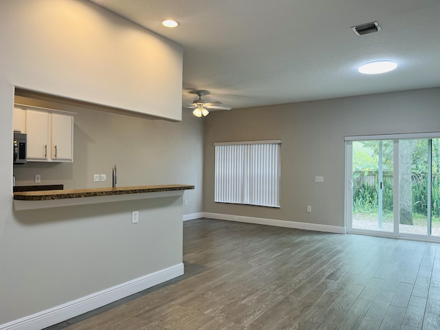117 Anchorage Ave Unit 6, Cape Canaveral, FL 32920 - kitchen featuring stainless steel microwave, ceiling fan, white cabinets, wood finished floors, and open floor plan