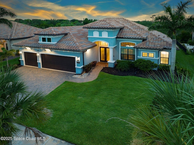 5197 Kirkwall Cir, Melbourne, FL 32940 - mediterranean / spanish house featuring a front lawn, an attached garage, a tile roof, and decorative driveway
