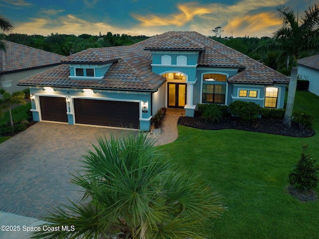 5197 Kirkwall Cir, Melbourne, FL 32940 - mediterranean / spanish-style home with a front yard, a garage, stucco siding, decorative driveway, and a tile roof