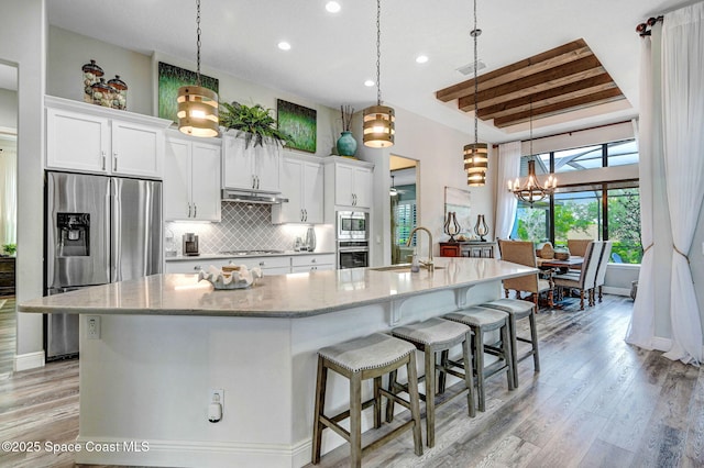 5197 Kirkwall Cir, Melbourne, FL 32940 - kitchen with appliances with stainless steel finishes, white cabinetry, light wood-style flooring, a large island, and decorative backsplash