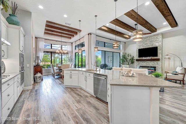 5197 Kirkwall Cir, Melbourne, FL 32940 - kitchen featuring appliances with stainless steel finishes, a tray ceiling, open floor plan, a stone fireplace, and a chandelier