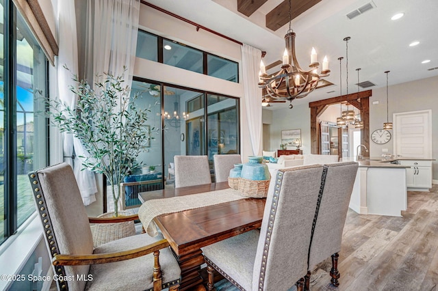5197 Kirkwall Cir, Melbourne, FL 32940 - dining room with a chandelier, light wood-style flooring, beamed ceiling, recessed lighting, and a towering ceiling