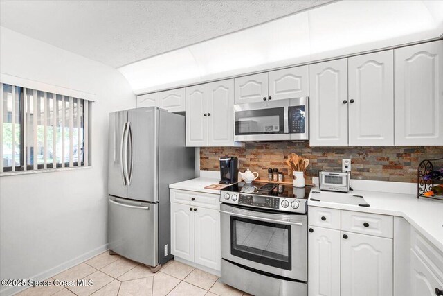 1611 Minutemen Cswy Unit 107-Hh, Cocoa Beach, FL 32931 - kitchen featuring appliances with stainless steel finishes, white cabinets, backsplash, and lofted ceiling