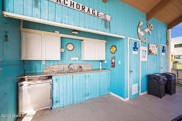 1611 Minutemen Cswy Unit 107-Hh, Cocoa Beach, FL 32931 - kitchen with carpet flooring, white cabinets, wood ceiling, and wooden walls