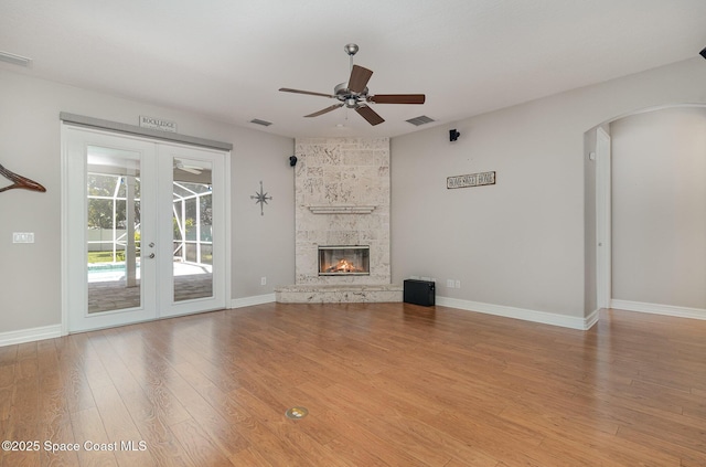 2351 Stonebridge Dr, Rockledge, FL 32955 - unfurnished living room with ceiling fan, french doors, arched walkways, wood finished floors, and a fireplace