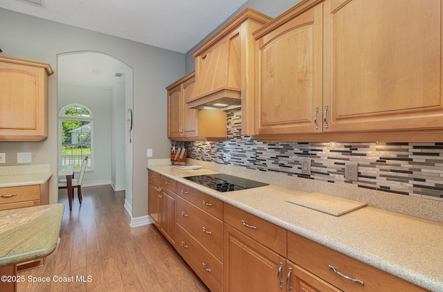 2351 Stonebridge Dr, Rockledge, FL 32955 - kitchen with black electric stovetop, light wood finished floors, backsplash, and arched walkways