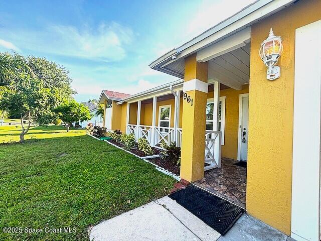 961 Haas Ave NE, Palm Bay, FL 32907 - view of home's exterior with covered porch, a yard, and stucco siding