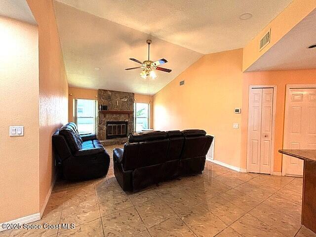 961 Haas Ave NE, Palm Bay, FL 32907 - living room featuring a ceiling fan, lofted ceiling, and a stone fireplace