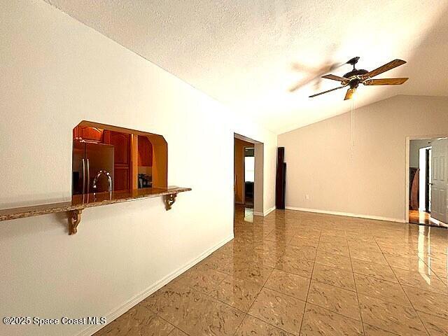 961 Haas Ave NE, Palm Bay, FL 32907 - spare room with vaulted ceiling, ceiling fan, tile patterned floors, and a textured ceiling