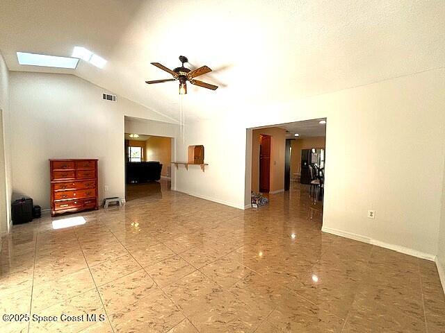 961 Haas Ave NE, Palm Bay, FL 32907 - unfurnished living room featuring ceiling fan, vaulted ceiling, and a skylight